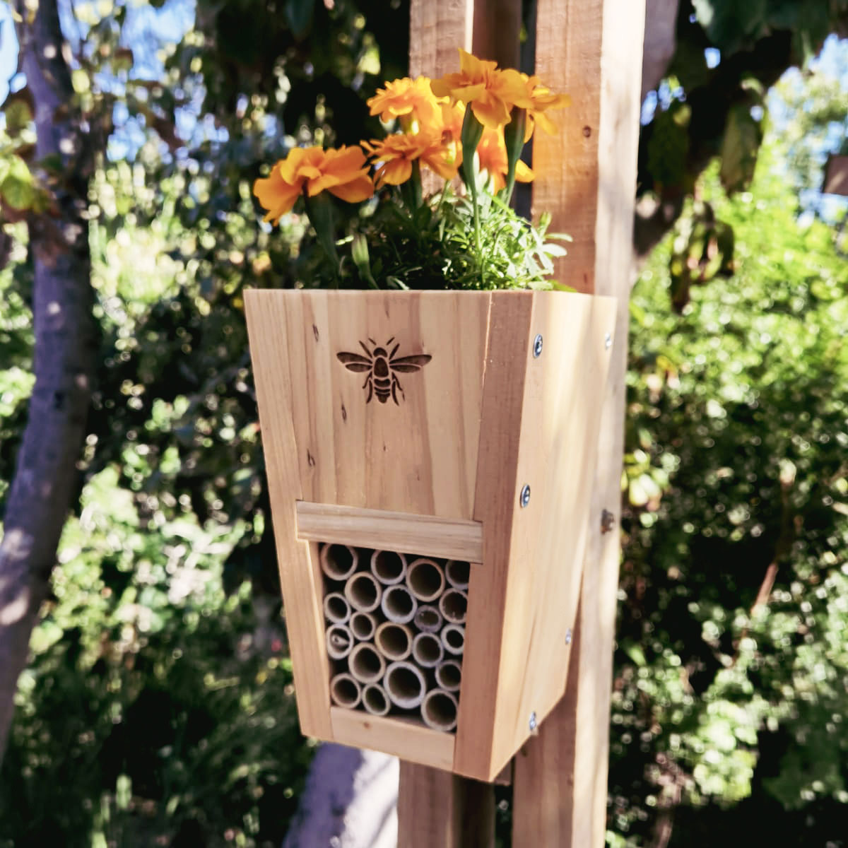 Wooden insect  house with floral top against a green outdoor background