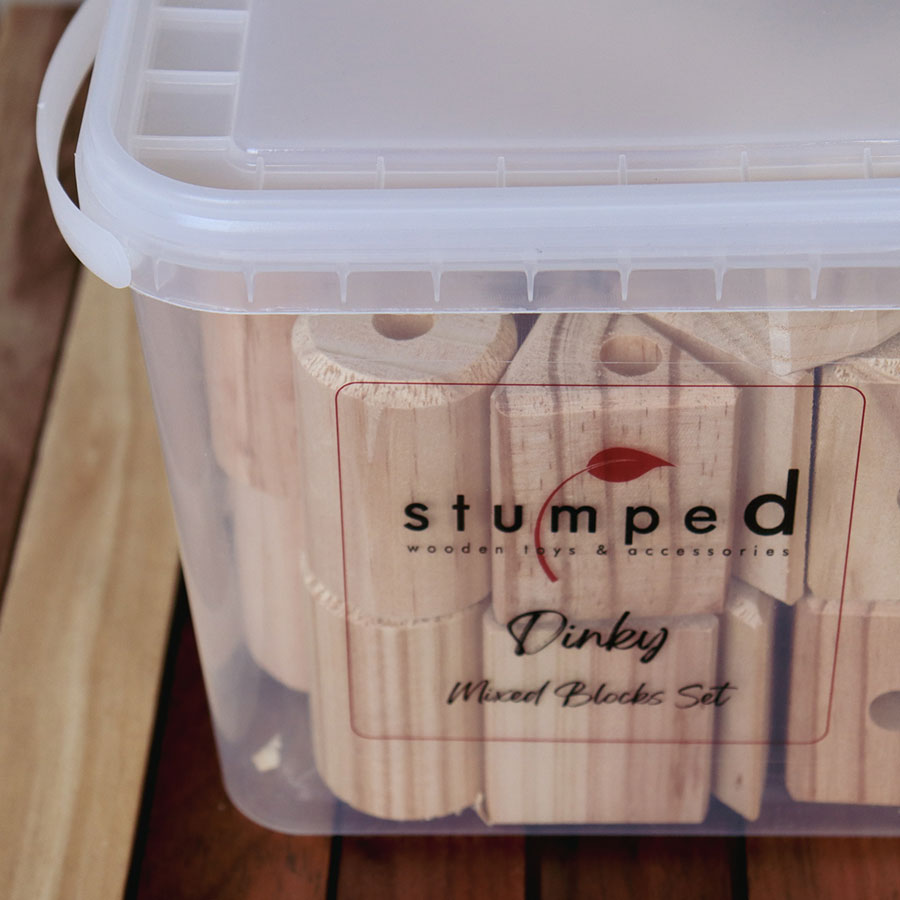 Clear container with wooden blocks labeled 'stumped' on a wooden surfac