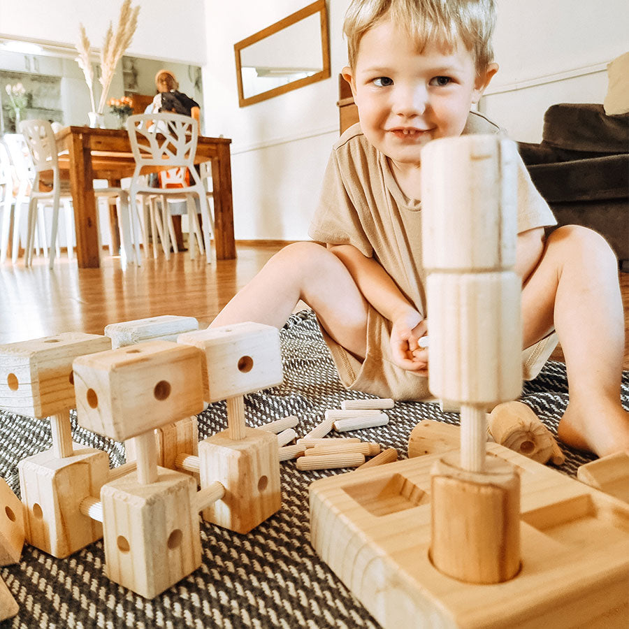 Child playing with wooden blocks on a rug in a living room.