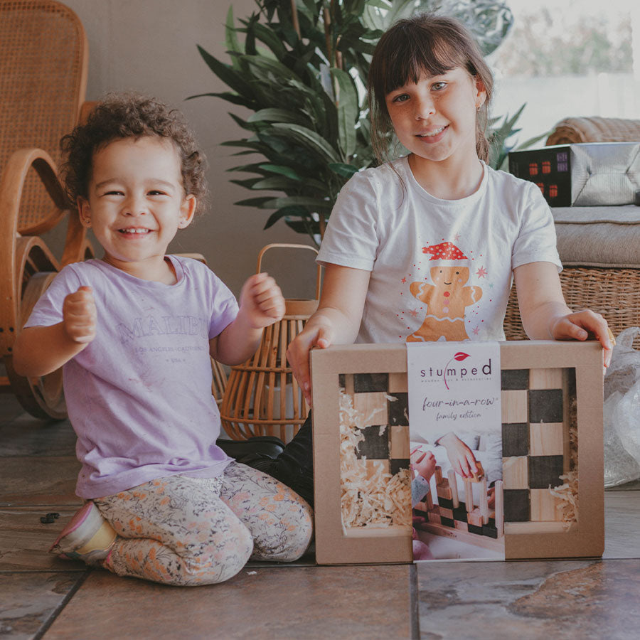 Two children sitting on the floor with a 'stamped' product box in front of them.