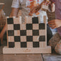Children playing with a wooden block puzzle resembling a castle, branded 'stumpad'.