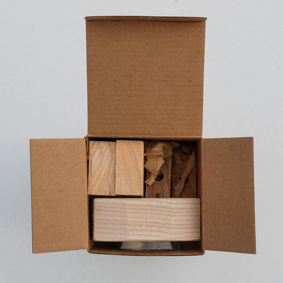 Open cardboard box containing wooden blocks on a light gray background